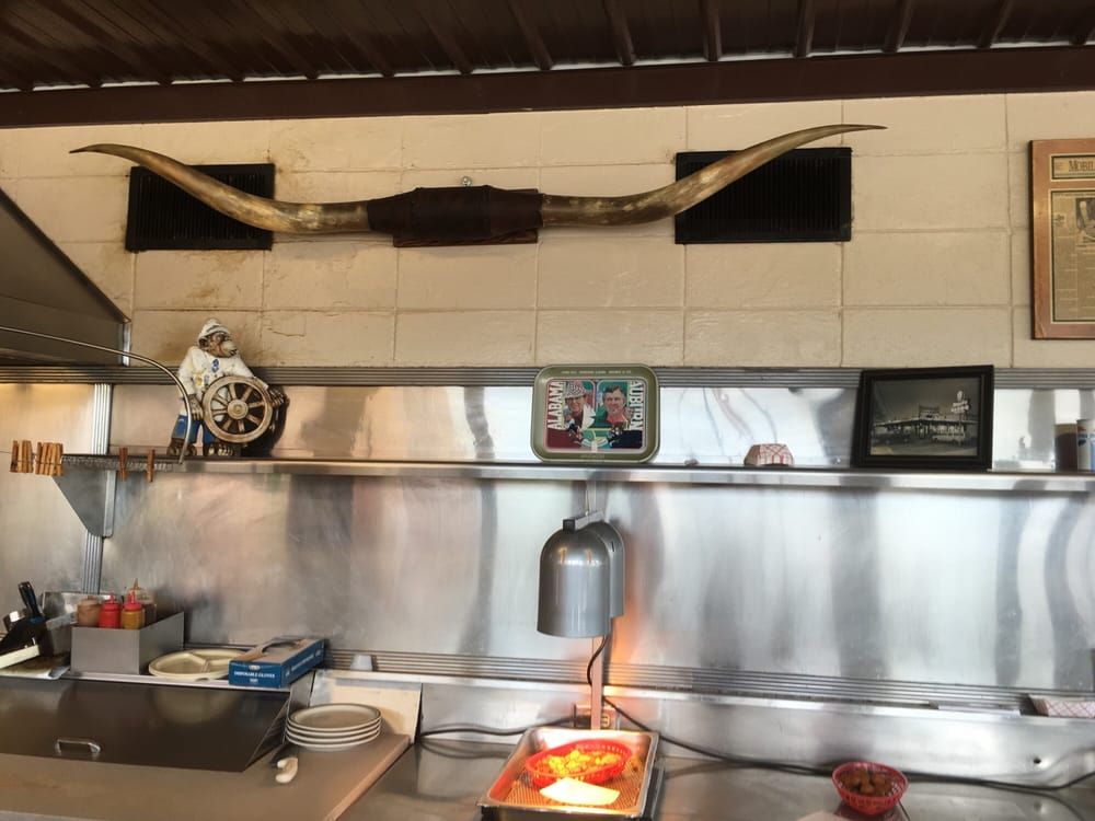 A pair of longhorn steer horns mounted on the wall above the stainless-steel shelf behind the counter