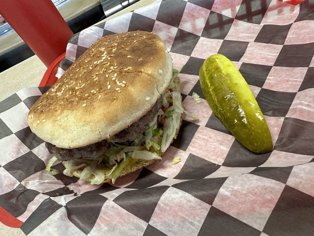 A Steer Burger at Roshell's: a big sesame-seed bun, lettuce and a pickle spear in a checked paper-lined basket